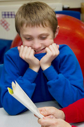 Boy listening to a story read by
                  his teacher