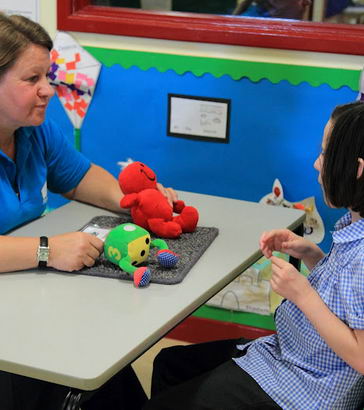 A teacher offers a girl a choice of two
                  toys