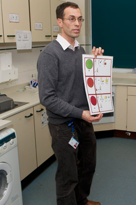 A teacher holds up a large card
                  indicating self-assessment symbols