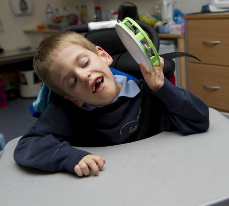 A boy plays with a small tambourine