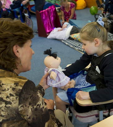 A teacher shows a girl a doll