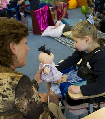 Using a doll a teacher interacts
                  a girl