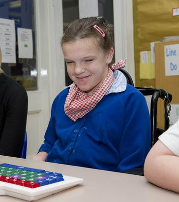 A girl and her teacher sit in
                  front of a keyboard smiling