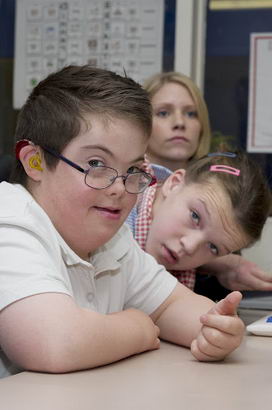 A boy and a girl in front of a
                  keyboard with their teacher