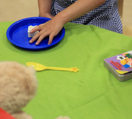 girl wearing head protection chooses a spoon
from a set of objects on a table