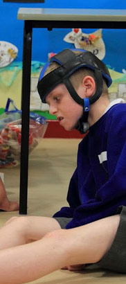 A boy looks at several objects presented
to him by a teacher