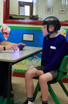 A girl wearing head protection looks at
a piece of paper held by her teacher