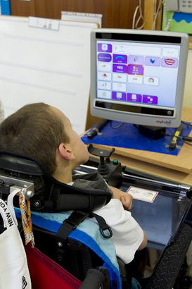 A teacher watches a boy use ICT
                  equipment