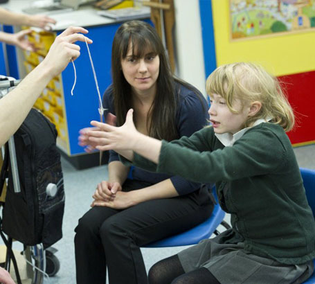 A girl is offered a choice of two objects
                  and reaches for a tennis ball