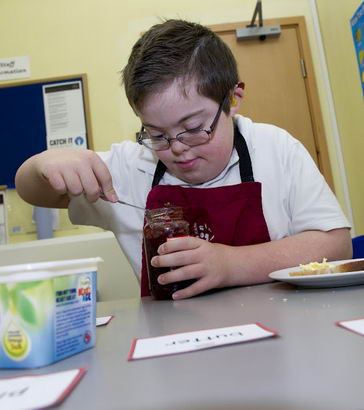 A boy prepares a jam sandwich