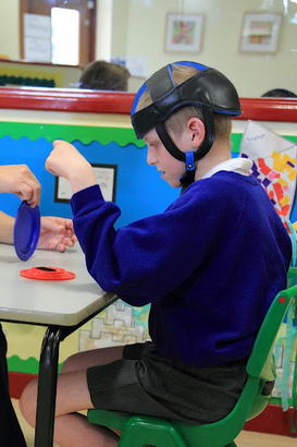 A teacher sits opposite a boy and shows
                  him different objects