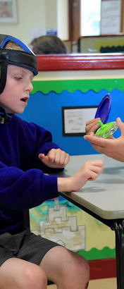 A teacher shows a boy two different objects