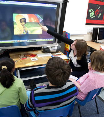 Three teachers and two students
                  use an interactive whiteboard to learn