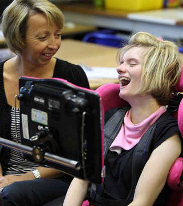 A teacher and two pupils with assistive
devices laugh and smile
