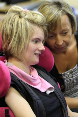 A teacher and girl use a computer with
the aid of an assistive device
