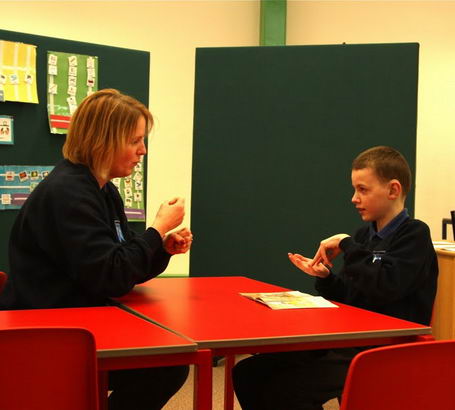 A boy and his teacher use British Sign Language