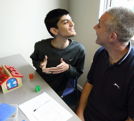Boy in grey Nike top smiles at the teacher
that he is sitting next to
