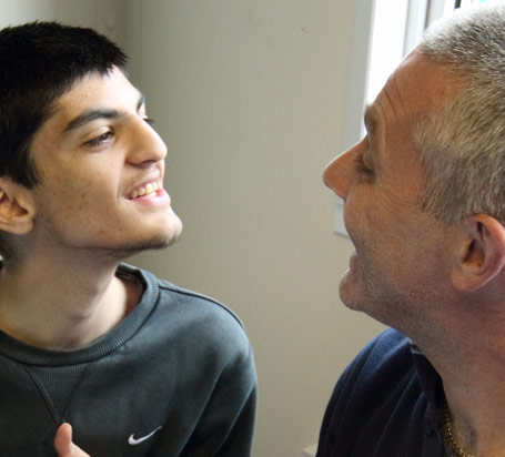 Boy in grey Nike top smiles at the teacher
that he is sitting next to