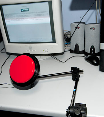 Articulated clamp holding large
red button in front of computer monitor