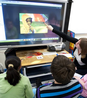 A teacher uses an interactive
board to engage with three of her pupils
