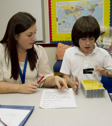 Teacher and young girl sit in front
                  of interactive ICT equipment