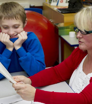 A teacher reads to a young boy