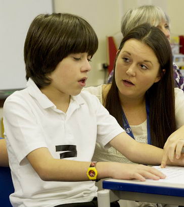 A young boy and teacher work through
                  a written exercise