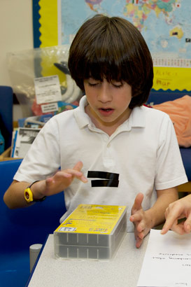 A young boy and his female teacher
                  sit side by side facing the camera