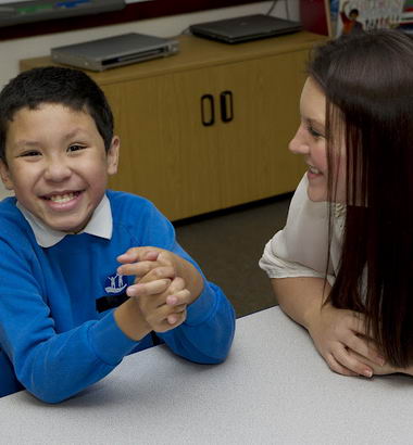 Young boy and female teacher fully
                  engaged at school desk