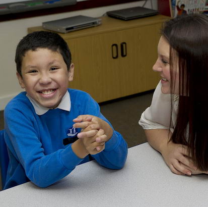 Young boy and female teacher at
school desk