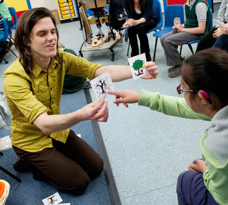 Male teacher using picture cards
                  with pupils