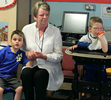 a young boy is consoled and comforted
by a male teacher who is halfway out of the frame