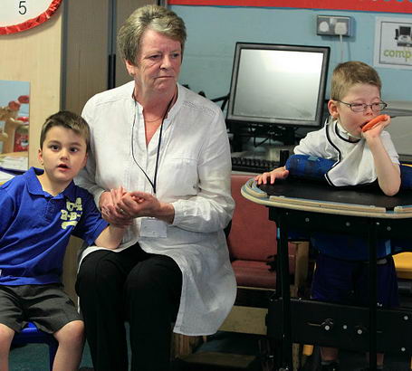 a young boy is consoled and comforted
                  by a male teacher who is halfway out of the frame