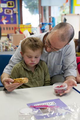 a young boy is consoled and comforted
                  by a male teacher who is halfway out of the frame