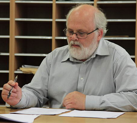 Gentleman with large grey beard sitting
at table carrying out an audit
