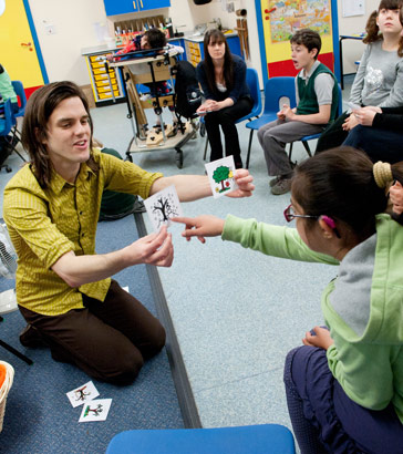 A girl points to a card held by
a teacher