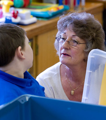 A teacher talking to a boy sitting
at a table