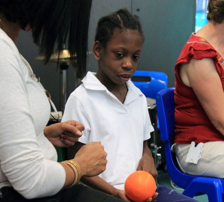 A male teacher smiles with one boy whilst
another boy lies on his lap