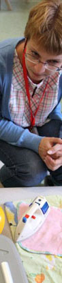 A male teacher smiles with one boy whilst
another boy lies on his lap