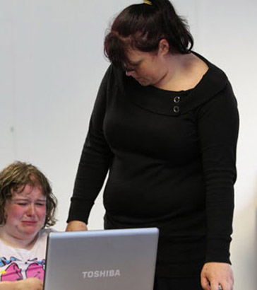 Two teachers comfort a distressed pupil
who is using a laptop