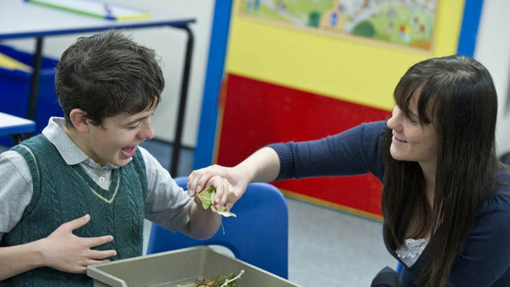 A teacher smiles at a boy laughing