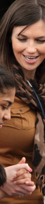 a teenage girl holds hands with her teacher
                  in a playground full of her peers