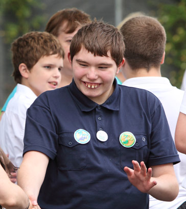 a teenage boy shakes hands with his teacher
in a playground full of his peers