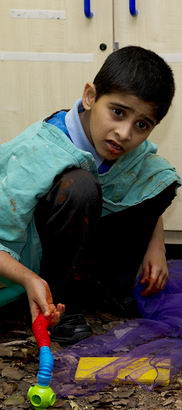 Young boy squatting in activity
                  area of classroom