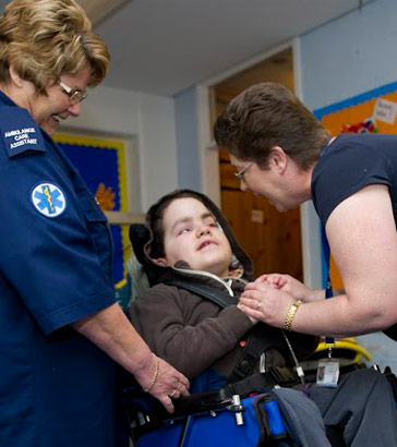 A boy in a wheelchair with two carers