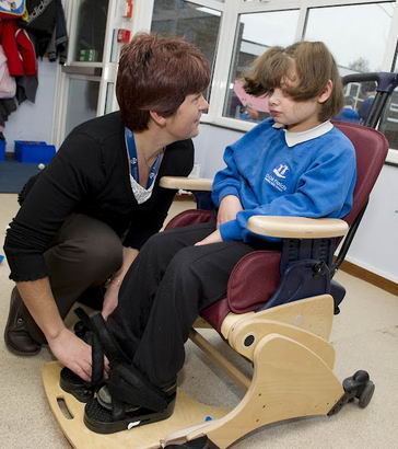 A carer helps to secure a girl
in a specialist chair