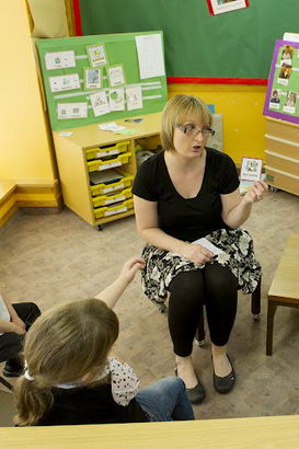 A teacher holds up a card in front
of several seated children
