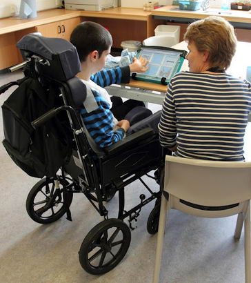 A speech therapist working with a boy
using a communcation device