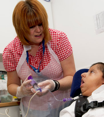 A carer helps to feed a boy via
a feeding tube