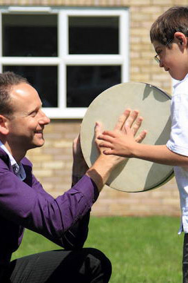 Teacher showing a boy how to play
the drum